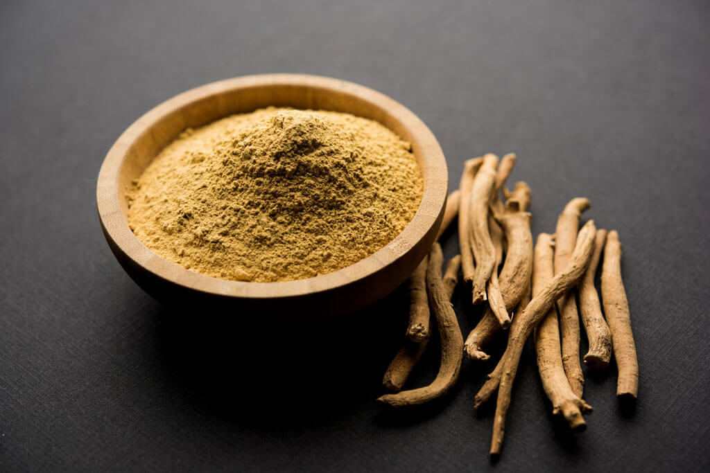 image showing ashwagandha sticks and powder in a wooden bowl