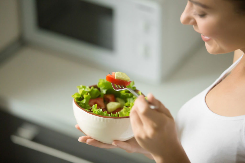 image showing a woman eating a green salad to boost their immunity