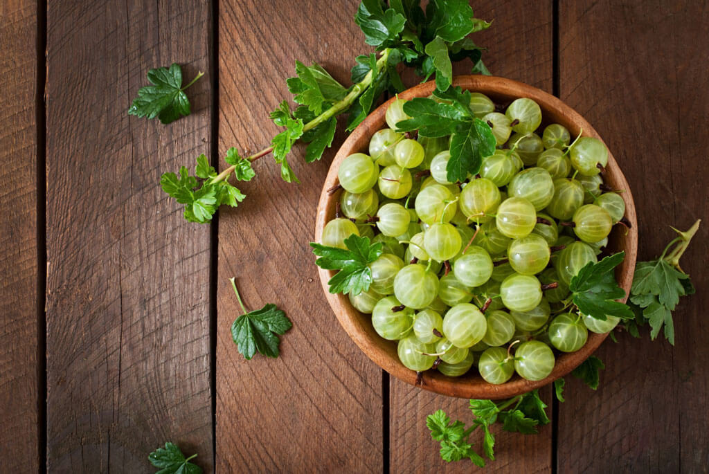 image showing amla or green gooseberries in a wooden bowl