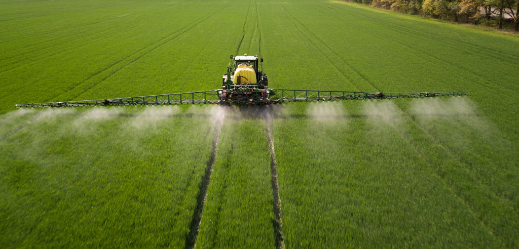 image shwoing the tractor spraying pesticides and chemical fertilizers in the fields