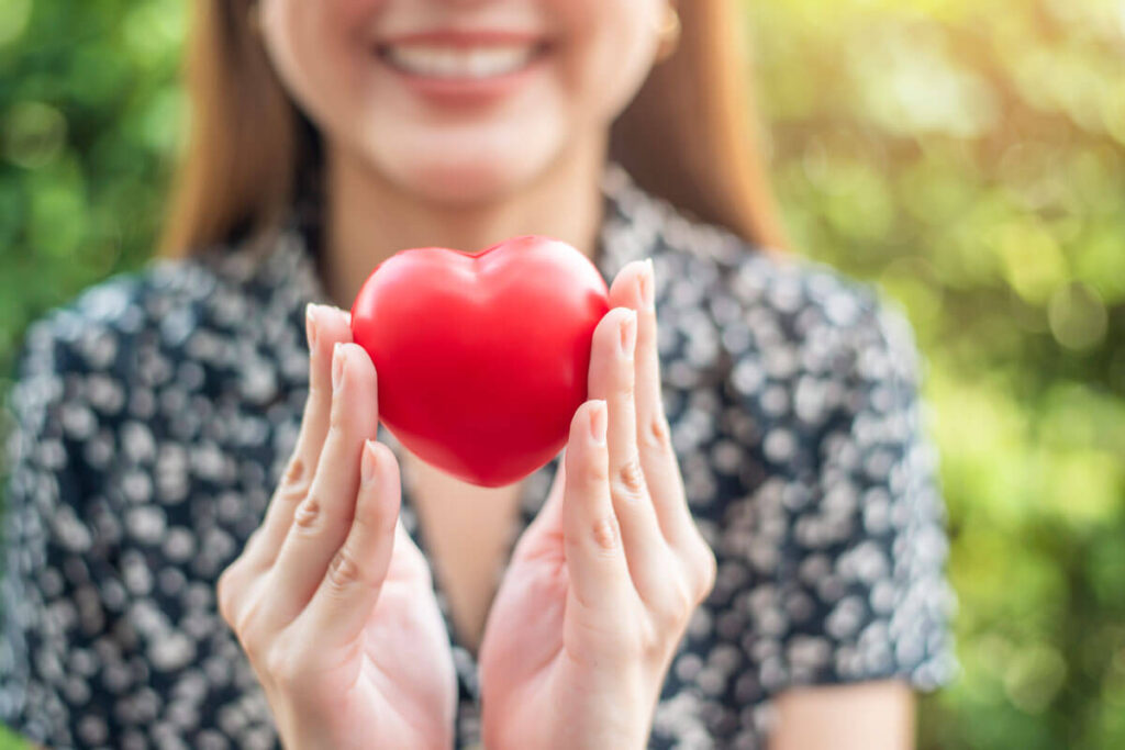 image of a woman holding red heart showing low cholesterol and improved health